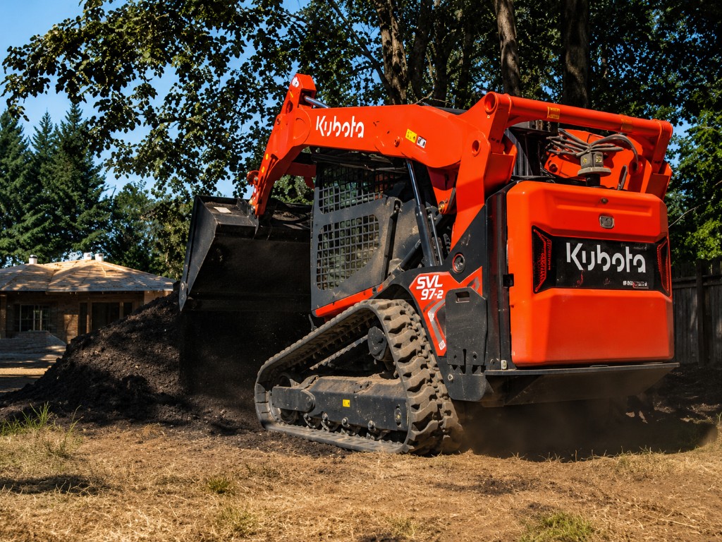 Kubota compact track loader moving wood chips and mulch during tree debris cleanup