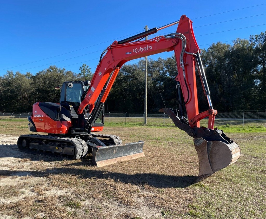 Orange mini excavator with thumb attachment for tree removal and land clearing